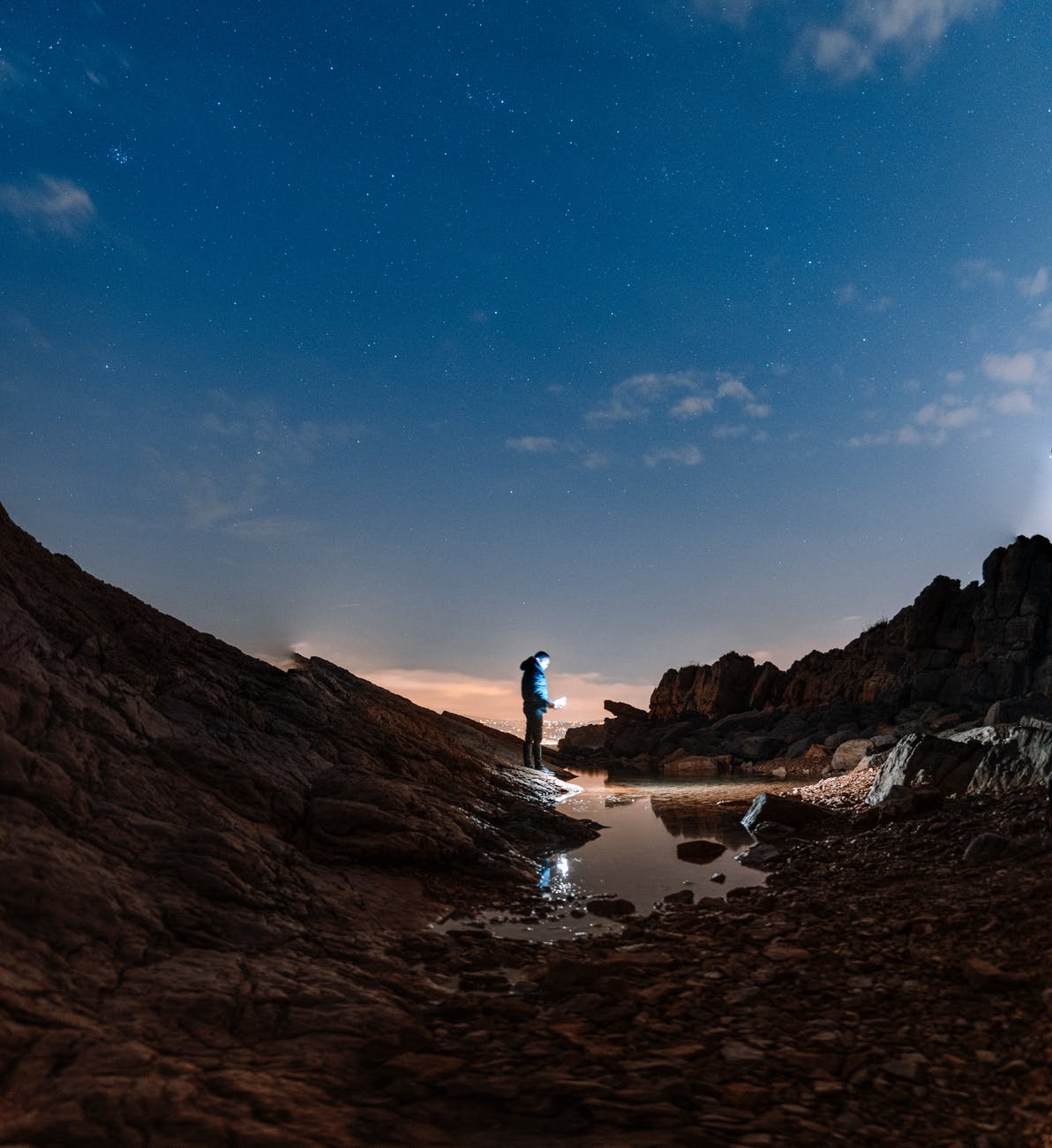 traveler standing on rocks at dusk